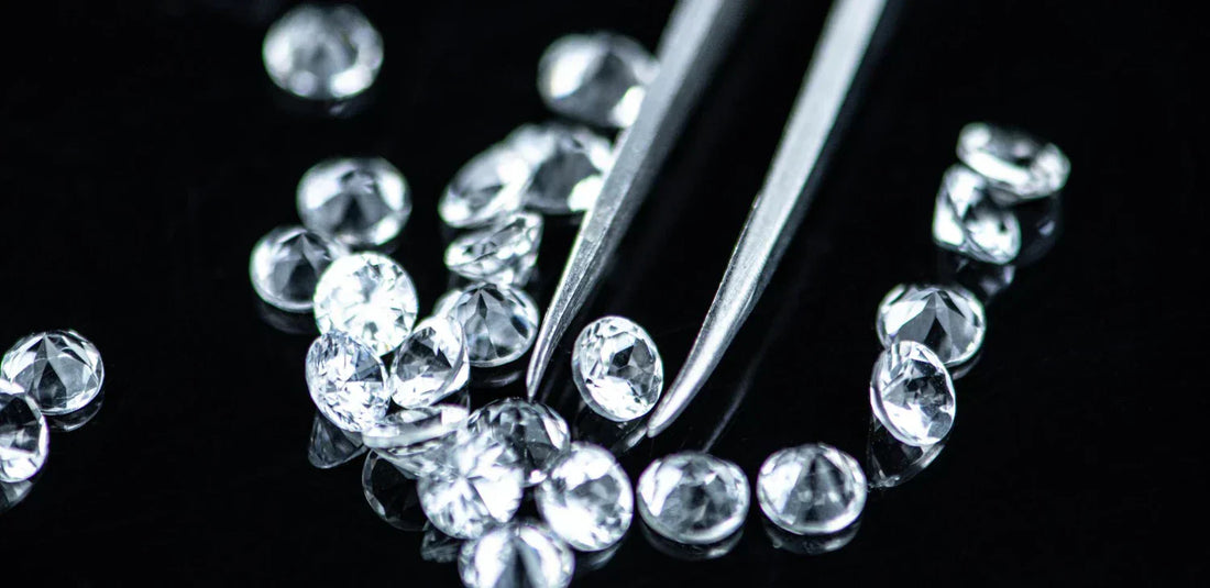 Small loose cubic zirconia stones with metal tweezers.